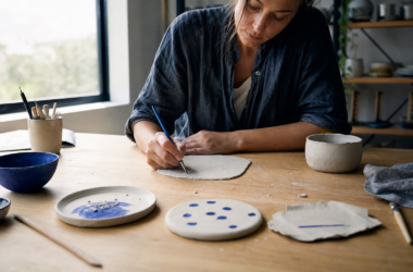 A woman beginning an imperfect handmade ceramic piece at a bright worktable