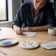 A woman beginning an imperfect handmade ceramic piece at a bright worktable