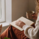 A person reflects beside a window with a journal and warm tea, representing a thoughtful connection to personal motivation.
