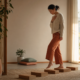 A woman taking gentle steps across wooden blocks in warm morning light